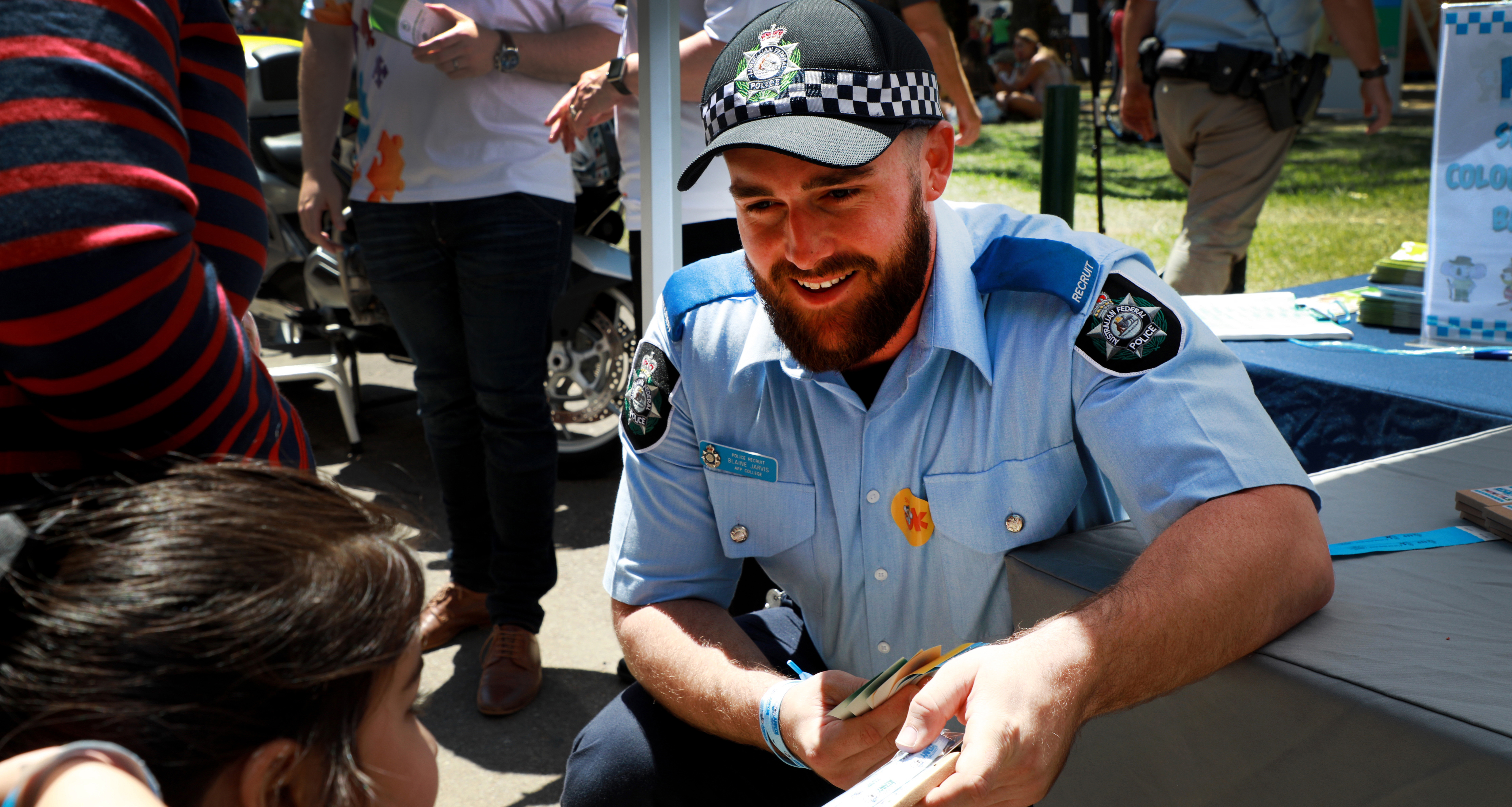 ACT Policing member hands out stickers at community event